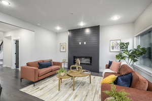 Living room featuring a large fireplace, wood finished floors, and recessed lighting