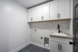 Laundry room with hookup for a washing machine, dark tile patterned floors, cabinet space, and electric dryer hookup