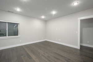 Unfurnished room with dark wood-type flooring and baseboards