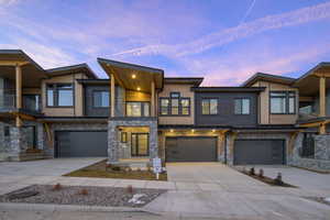 Modern home featuring a balcony, stone siding, concrete driveway, and an attached garage
