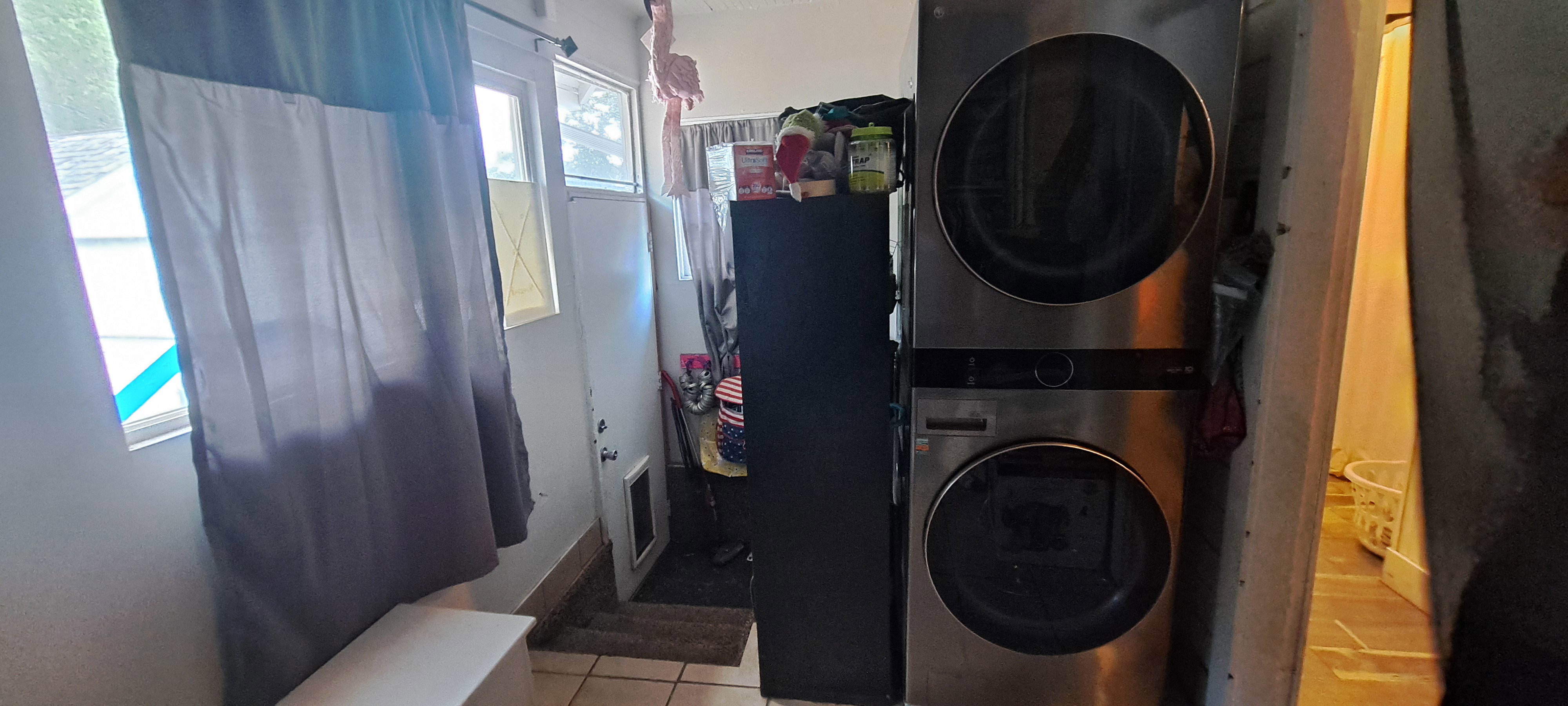 Washroom with stacked washer / dryer and tile patterned flooring