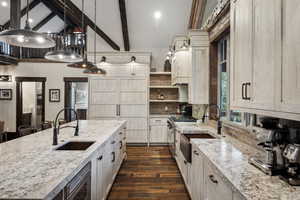Kitchen featuring pendant lighting, dark wood-type flooring, decorative backsplash, light stone countertops, and beamed ceiling