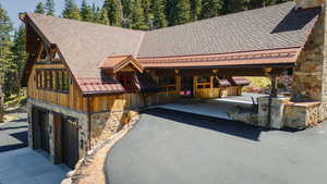 View of front of house featuring stone siding, a shingled roof, and driveway