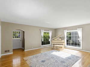 Living room with arched walkways, healthy amount of natural light, and wood finished floors