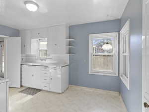Kitchen featuring light countertops, healthy amount of natural light, and white cabinets