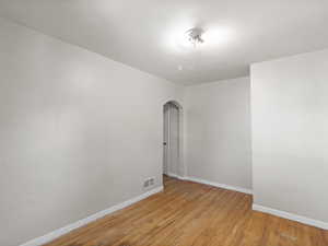 Empty room featuring arched walkways and light wood-type flooring