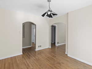 Spare room featuring arched walkways and light wood-style floors