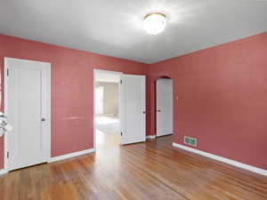 Unfurnished room featuring arched walkways and light wood-type flooring