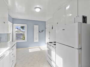 Kitchen featuring white appliances, tile countertops, and white cabinets