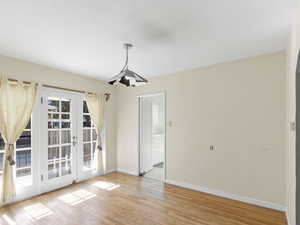 Unfurnished dining area with french doors and light wood-style flooring