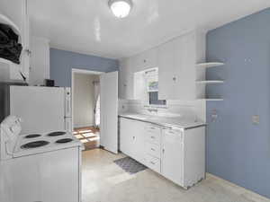 Kitchen with white appliances, light floors, light countertops, and open shelves