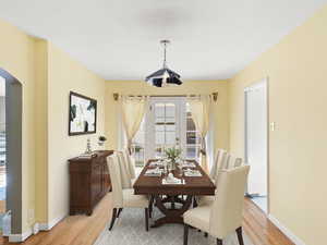 Dining room with light wood-type flooring and arched walkways
