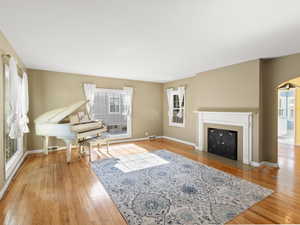 Living room with wood finished floors, a fireplace with flush hearth, and arched walkways