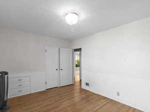 Unfurnished bedroom with wainscoting and wood finished floors