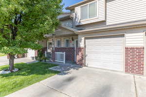 View of front facade with brick siding, a porch, concrete driveway, and a garage