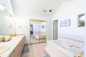 Bathroom with double vanity, a bath, tile patterned floors, and high vaulted ceiling