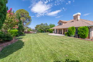 View of green lawn featuring a trampoline and a patio area