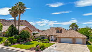 View of front of property featuring a front yard, a garage, driveway, brick siding, and a tiled roof