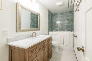 Bathroom featuring vanity, a textured ceiling, and washtub / shower combination