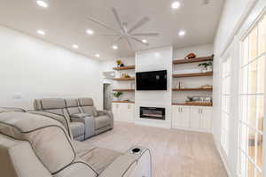 Carpeted living room with a ceiling fan, a large fireplace, and recessed lighting