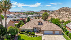 View of front of house featuring an attached garage, driveway, a mountain view, a front lawn, and brick siding