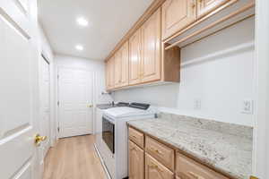 Washroom with washer and clothes dryer, cabinet space, light wood-style floors, and recessed lighting