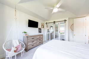 Bedroom featuring a barn door, lofted ceiling, a ceiling fan, and access to outside