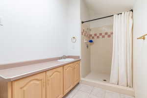 Bathroom featuring tile patterned floors, a tile shower, and vanity