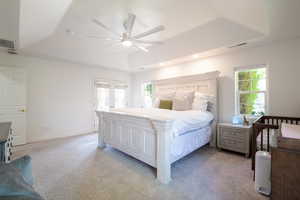 Bedroom featuring a tray ceiling, light carpet, and ceiling fan