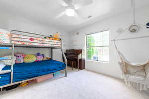 Carpeted bedroom featuring ceiling fan and baseboards