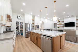 Kitchen featuring appliances with stainless steel finishes, open shelves, open floor plan, ceiling fan, and white cabinetry
