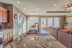 Kitchen with wood finished floors, light stone countertops, recessed lighting, open floor plan, and brown cabinetry