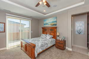 Bedroom with access to exterior, light colored carpet, a raised ceiling, and ceiling fan
