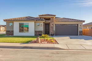 Mediterranean / spanish-style house with stone siding, driveway, an attached garage, a front yard, and a tiled roof