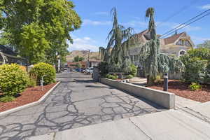 View of asphalt road with a gate, a mountain view, a gated entry, and curbs