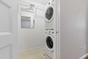 Laundry room featuring estacked washer and dryer and baseboards