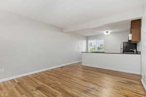 Unfurnished living room with light wood-style floors and baseboards