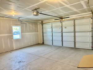 Large sized two-car garage featuring a garage door opener, faucet and outlet for your car