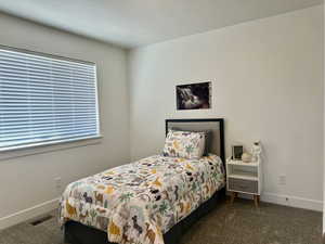Bedroom with dark colored carpet and baseboards with a generous closet space