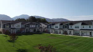 Traditional home featuring stone siding, a residential view, a mountain view, and a front yard