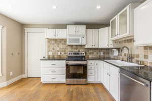 Kitchen with stainless steel appliances, tasteful backsplash, white cabinetry, and recessed lighting