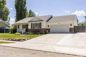 Ranch-style home featuring brick siding, an attached garage, driveway, and covered porch