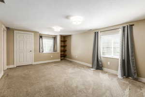Unfurnished bedroom featuring light carpet and baseboards