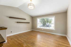 Empty room with light wood finished floors and lofted ceiling