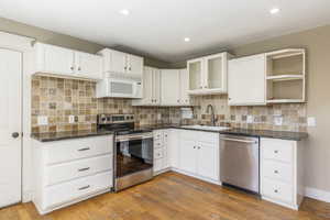 Kitchen featuring stainless steel appliances, white cabinetry, light wood finished floors, and recessed lighting