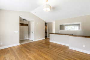Unfurnished living room featuring light wood-style flooring and vaulted ceiling