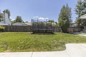 Fenced backyard featuring a trampoline
