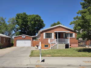 View of front of house featuring concrete driveway, brick siding, and an outbuilding