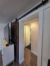 Hall with wood finished floors, a barn door, and a textured ceiling