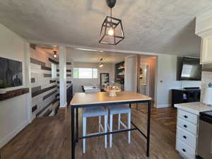 Kitchen with dark wood-style floors, light countertops, white cabinetry, and hanging light fixtures